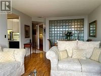 Loveseat shown installed in a living room, cream/beige floral upholstery, decorative pillows on seat and back cushions