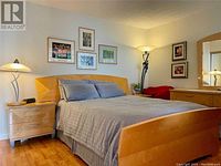 Queen bed setup with tan/golden wood geometric pattern headboard, side tables with lamps in a bedroom setting.
