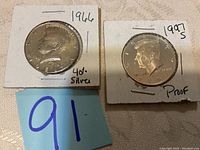 Photo of front side of 1966 40% silver half dollar and 1997 S Proof half dollar secured in holders with handwritten labels.