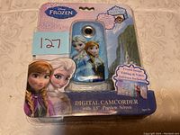 Front view of the digital camcorder packaging displaying images of Elsa and Anna from Disney Frozen, showing the camera lens and software inclusion.