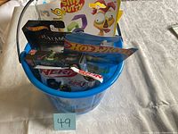 Front view of the blue Halloween bucket filled with toys including Hot Wheels Batman car, Silly Putty, Nerf Galaxy Blaster, Robo Chimp Robot, and more.