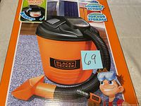 Front view of Black & Decker Junior Vac toy vacuum in orange and black with hose and nozzle attached, showing the product label clearly.