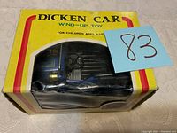 Front view of the Dicken Car wind-up toy in its original yellow box with clear plastic window showing the blue and black car inside.