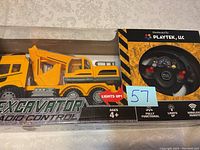 Photo showing unopened boxed yellow excavator radio control truck and its remote control unit on the right side in packaging.