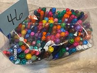Top view of mixed markers in a resealable plastic bag showing a wide range of colors and tip caps.