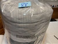 Quilt rolled and sealed in clear plastic packaging with warning label visible, showing its condition and packaging.