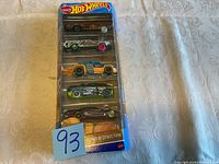 Photo of Hot Wheels Demo Destruction set showing all five cars in blister packaging on a white patterned cloth surface.