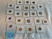 Photo showing 23 uncirculated US coins arranged on a surface, each in individual protective holders with years and condition markings.