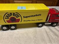 Front side view of the yellow and red ShopRite die cast truck showing the cab and part of the trailer with ShopRite Supermarkets branding and tagline.