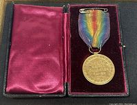 World War I Victory Medal in open black hinged display case showing both medal and purple velvet/silk interior.