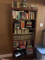 Full front view of the bookshelf showing multiple shelves filled with books and VHS tapes at the bottom.
