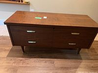 Front view of stained wooden cedar chest with metal drawer handles and tapered legs.
