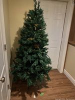 Full artificial Christmas tree about 6ft tall standing in corner with white door background