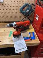 Black & Decker cordless drill with instruction manual on wooden bench