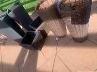 Six garden pots arranged on a patio, four round brown ones and two square black ones, showing their size and shape