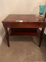 Front view of occasional table showing wooden top with inlaid design and lower shelf