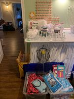 Photo showing two large bins with assorted Christmas fabric, sewing supplies racks, pillow form, black wire dress form, and knitting basket with yarn.