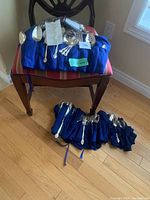 Photo of the complete set of silverware laid out on blue dust wraps on and under a chair showing all pieces.