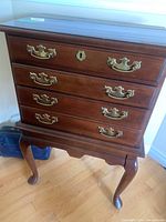 Front view of the wood silverware chest showing brass handles and keyhole.