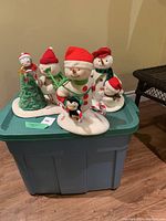 Five Hallmark snowmen plush figures on a lid of plastic bin, showing their overall look and accessories