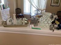 Wide shot showing glassware, trays, white ceramic jug, and decorative items on shelf