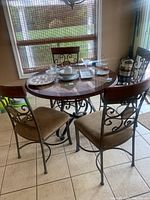 View of four dining chairs with metal scroll backrest and taupe fabric seats around table.