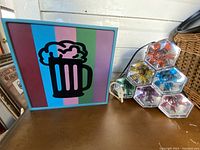 Photo showing the colorful square electric light with striped background and beer mug design alongside the stack of hexagonal shaped colored bulb lights.