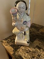 Front and side view of the porcelain Asian statue showing detailed robe and facial features