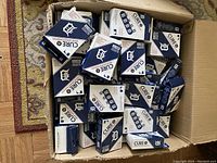 Photo of open cardboard box filled with multiple small boxes of MLB Detroit Tigers adhesive bandages with blue and white packaging