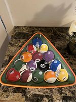 Triangular ceramic tray with raised clay art pool balls arranged inside, placed on a marble surface, shown from a slightly elevated angle.