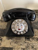 Front view of the black ceramic cookie jar shaped as an old-fashioned rotary dial telephone with a face on the dial.