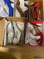 Top-down photo showing 4 pairs of ladies high heel shoes in boxes: silver glitter pumps, blue pumps, leopard print stilettos, red heels.