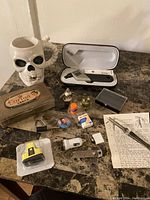Photo showing the full assortment of miscellaneous items including the skull mug, cigar tin, small tools, vials and pen.