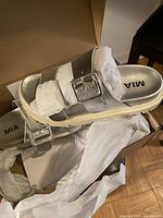 Photo of new MIA metallic silver women's sandals size 7M in box with tissue paper, showing two wide straps with adjustable buckles and cushioned footbed.