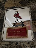 Front view of the rectangular vintage Johnnie Walker Red Label bar mirror with the striding man figure and red label text.