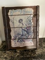 Front view of vintage wooden advertising sign for Burpee Seeds dated 1889 with colorful illustration and text.