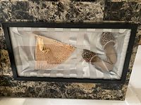 Full view of shadow box with slippers and fan on silver satin backing