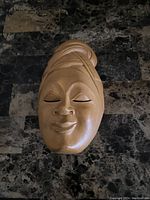 Front view of the carved wooden face mask showing facial features and head wrap detail.