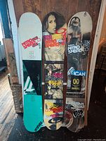 Photo showing all three snowboard decks side by side, highlighting varied graphic art and general wear.