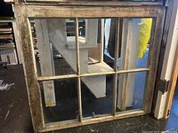 Front view of antique window showing six intact glass panes and weathered white wooden frame.