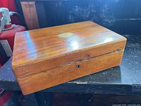 Closed wooden apothecary box showing polished wood and brass keyhole without key