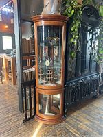 Frontal view of wooden corner curio cabinet loaded with decorative items to show shape and design