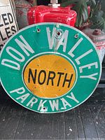 Front view of the Don Valley Parkway North road sign showing text, colors, and damage including holes and dents.