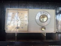 Front view showing the clock face on the left and the radio tuning dial with knobs on the right side of the vintage General Electric radio.