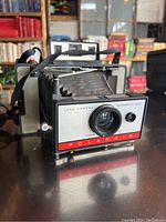 Front angle view showing the lens, shutter button, and Polaroid branding on the front panel with bellows extended.