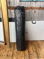 Front view of standing black punching bag with metal rings visible
