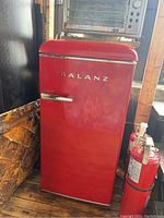 Photo of red Galanz bar fridge showing full front with chrome handle and logo.