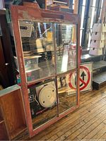 Front view of the weathered red wooden vintage window with four visible glass panes showing signs of dirt and wear on the frame.