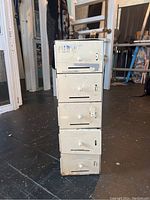 Front view of the small white metal locker with four compartments, showing wear and some discoloration.