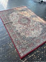 Full view of vintage oriental style area rug on wooden floor showing overall design and condition.